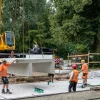 Baustellenansicht an der Haltestelle Reiterstadion, wo ein Kran 8 Tonnen schwere Betonteile von einem Tieflader für den künftigen Hochbahnsteig ablädt.