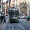 Stark abgenutzte, in das Pflaster eingebettete Stadtbahngleise in der Fußgängerzone der Limmerstraße in Hannover-Linden mit vorbeirollendem Straßen- und Radverkehr.